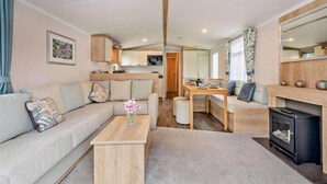 A modern RV interior with a living area, kitchen, and dining space.