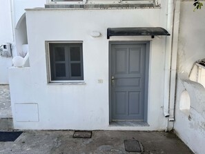 Un bâtiment blanc avec une porte grise et une petite fenêtre.