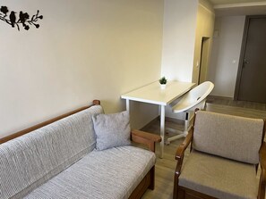Un salon moderne avec un canapé à rayures, une petite table blanche ornée d’une plante et une chaise blanche.