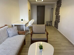 Ein modernes Wohnzimmer mit einer Couch, einem Sessel und einem kleinen Tisch mit einer Pflanze.