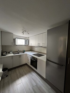A modern kitchen with white cabinets, stainless steel appliances, and a built-in oven. - Charming Getaway in the Heart of Emporio Santorini (Santorini)