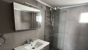 Une salle de bain moderne avec un grand miroir, un lavabo et une douche.