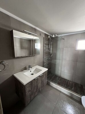 Ein modernes Badezimmer mit einem großen Spiegel, einem Waschbecken und einer Dusche.