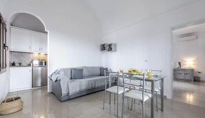 Un espacio habitable moderno y minimalista con sofá, mesa de comedor y zona de cocina.