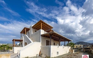 A modern two-story house with a flat roof and a covered patio area.