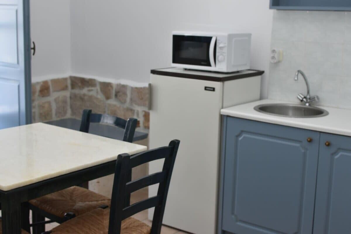 Cocina compacta equipada con microondas, lavamanos y comedor con mesa y sillas.