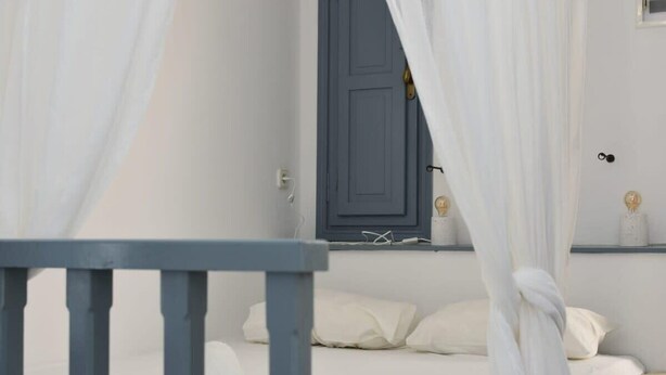 A bedroom with a bed, white curtains, and a blue door. - Relaxing Patmos Studio by the Aegean No 3 (Patmos)