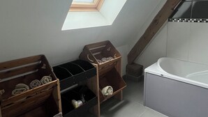 A small, sloped-roofed room with a skylight, wooden storage units, and a bathtub. - Les Buissonnets - Maison de Campagne à 10 Minutes de la Plage de Wissant (Peuplingues)