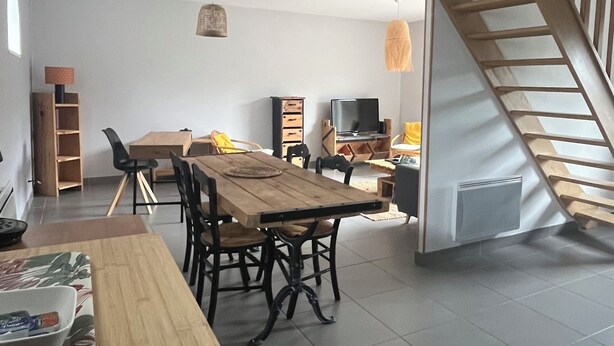 A spacious living area with a wooden dining table, chairs, and a staircase. - Les Buissonnets - Maison de Campagne à 10 Minutes de la Plage de Wissant (Peuplingues)