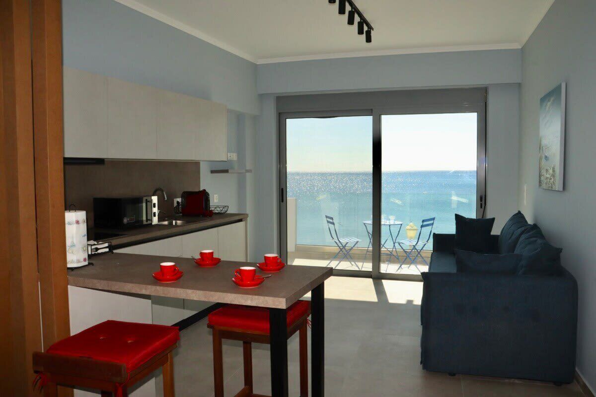 Een moderne keuken met een eethoek, een balkon met uitzicht op zee, en een blauwe bank.