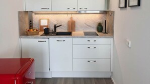 A compact kitchen with white cabinets, a countertop, and a red appliance. - Bright & Charming Studio at Alexanderplatz (Berlin)
