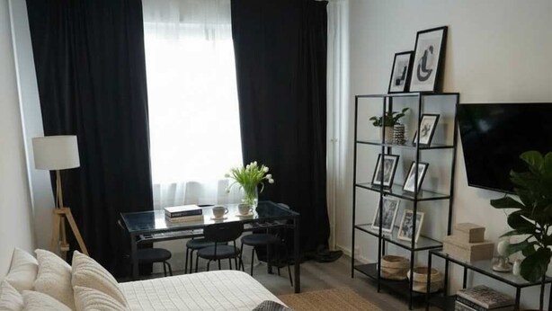 A hotel room with a large bed, a desk with a chair, a bookshelf, and a TV. - Bright & Charming Studio at Alexanderplatz (Berlin)