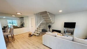Een moderne woonkamer met een trap, een bank, een televisie en een ventilator.