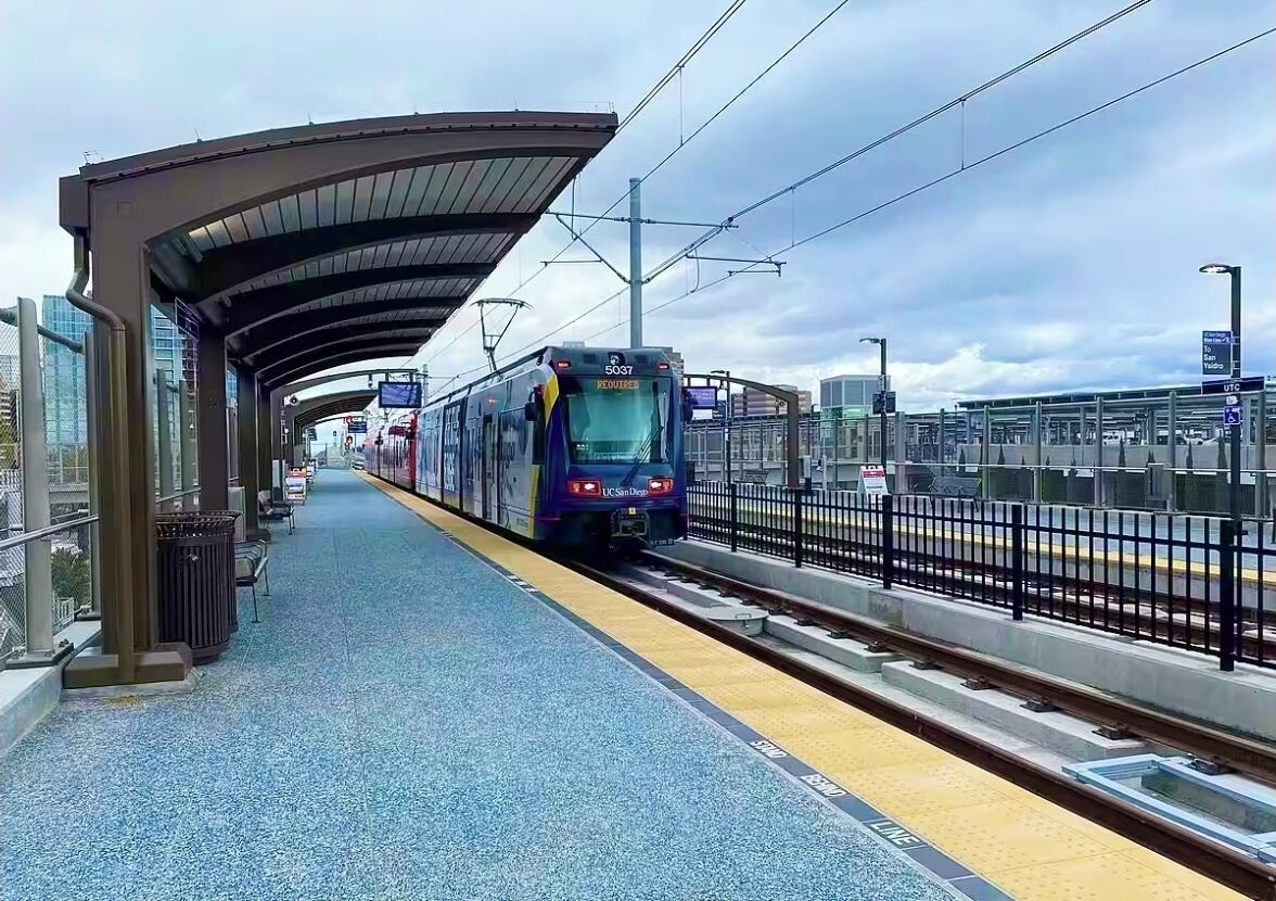 A train station platform with a covered waiting area and a train approaching.