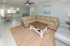 A living room with a sectional sofa, a wooden coffee table, and a patterned rug. - 5 BR Walk to the Beach House with a Private Pool! The Salty Seagull (Surfside Beach)