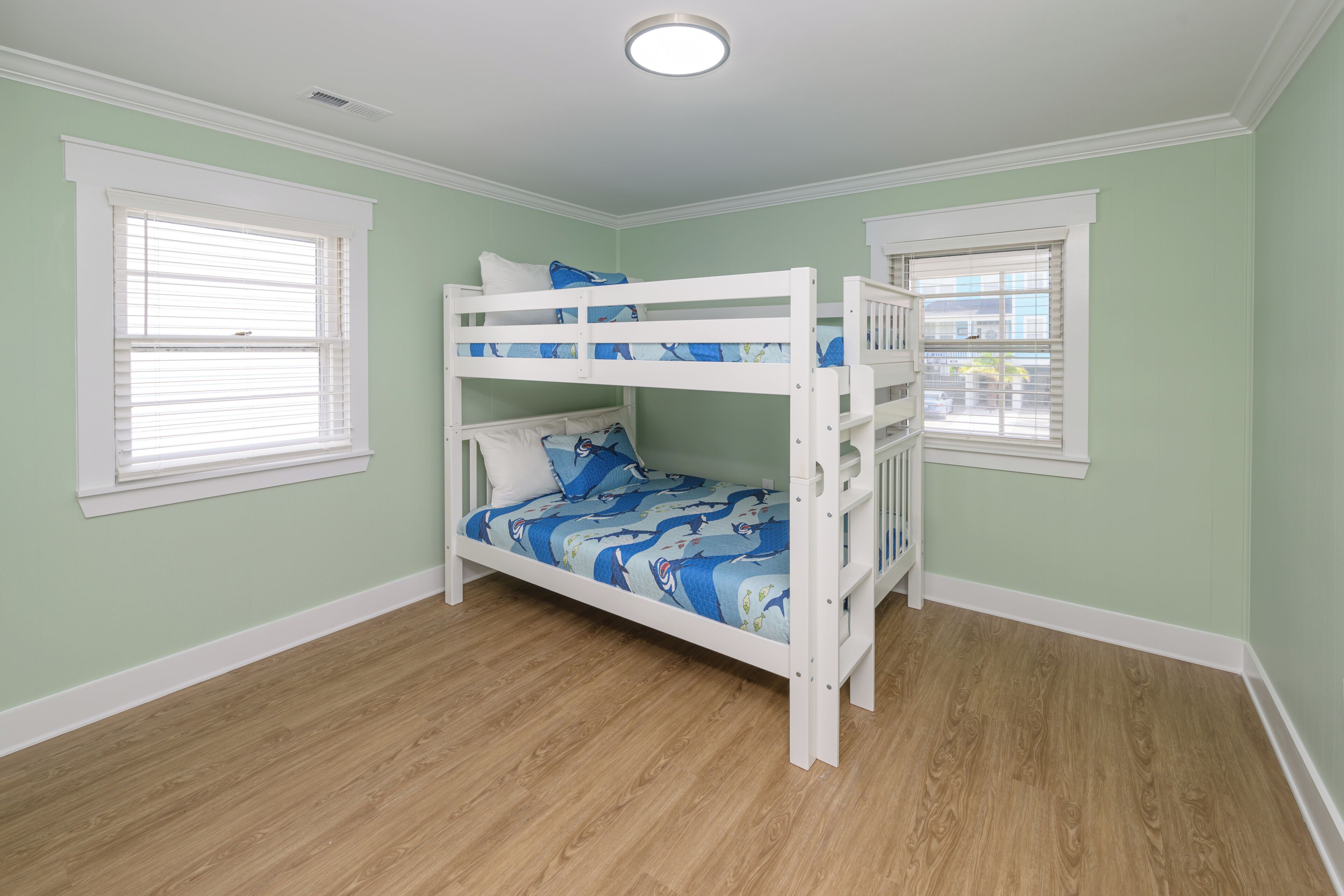 Dormitorio con literas, ventana, luz de techo y suelo de madera.