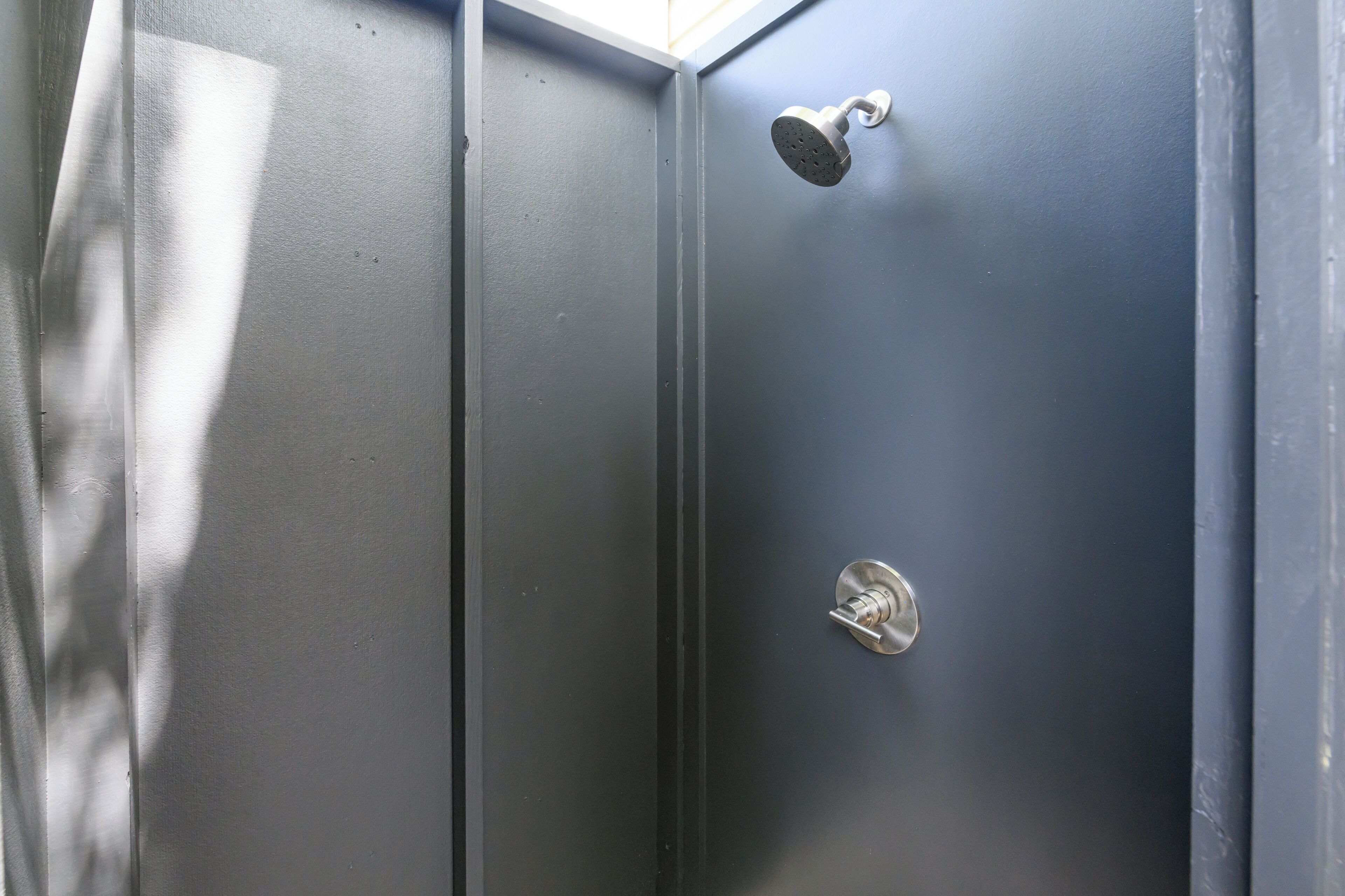 A metallic door with a showerhead and a lock.