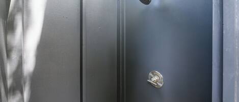 A metallic door with a showerhead and a lock.