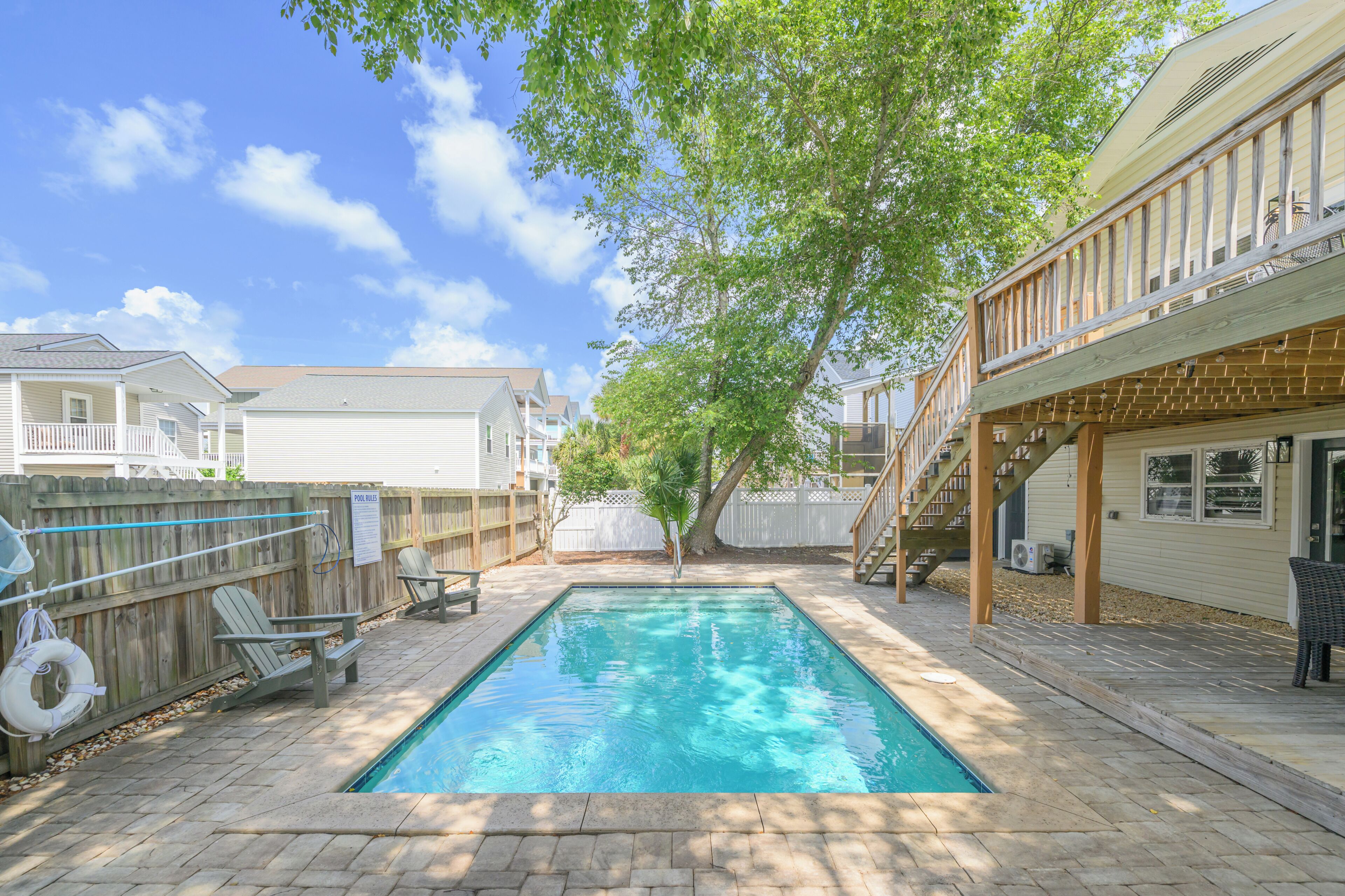 Un jardin avec une piscine, une terrasse en bois et un espace couvert avec un escalier.