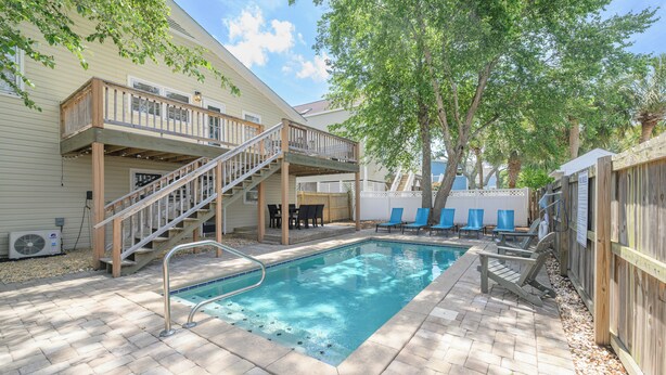 Ein Garten mit Schwimmbad, Holzterrasse und überdachter Terrasse.