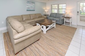 A living room with a beige sectional sofa, a grey sofa, a wooden coffee table, and a patterned rug. - 5 BR Walk to the Beach House with a Private Pool! The Salty Seagull (Surfside Beach)
