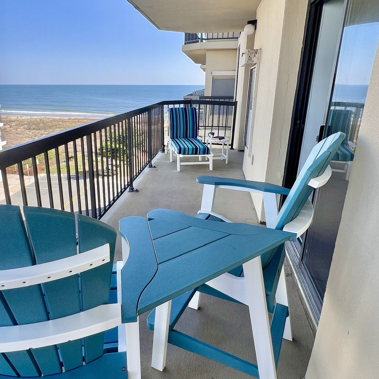 A balcony with a view of the ocean, featuring two chairs and a table.