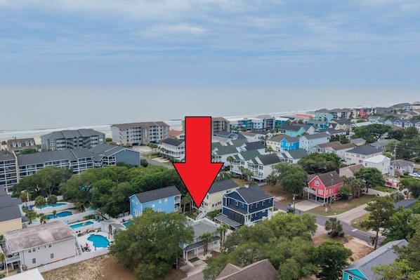 Un quartier résidentiel avec des maisons, une piscine et une plage en arrière-plan.