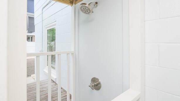 A white shower enclosure with a showerhead and a control knob.
