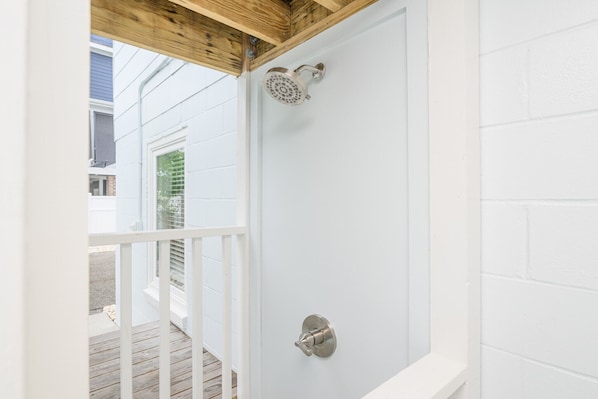 A white shower enclosure with a showerhead and a control knob.