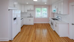 A kitchen with white cabinets, a refrigerator, a sink, and a window.