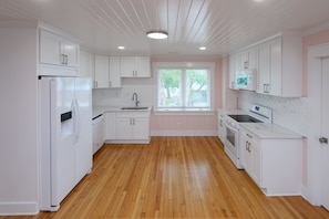 A kitchen with white cabinets, a refrigerator, a sink, and a window.