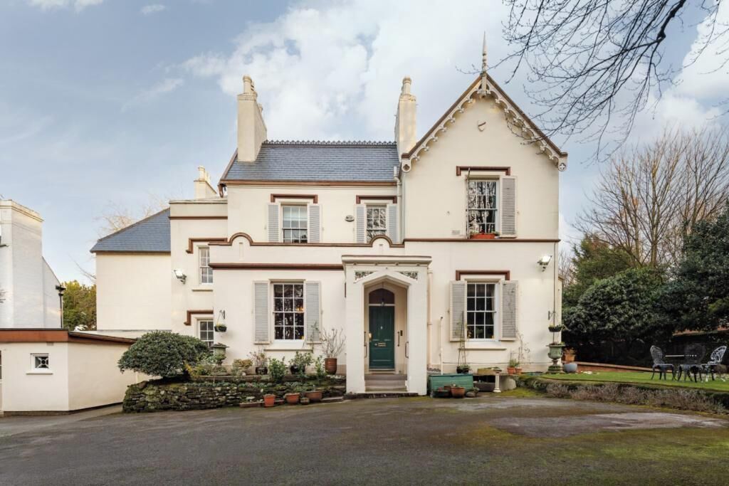 A two-story house with a symmetrical facade, a central entrance with a green door, and a small front garden.
