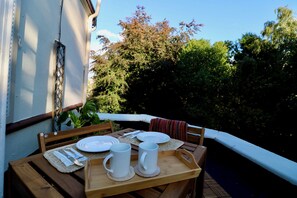 A wooden table set with plates, cutlery, and white mugs on a balcony with a view of trees and a building. - Mossley Hill Retreat (Liverpool)