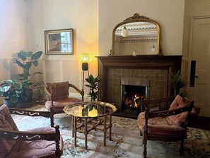 A cozy living room with a fireplace, two armchairs, a small round table, and a mirror above the fireplace. - Mossley Hill Retreat (Liverpool)