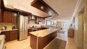 A modern kitchen with a large island, stainless steel appliances, and wooden cabinetry. - Stunning ocean vistas, near top surf spots, shops; private, all amenities. (Jeffreys Bay)