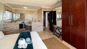 A hotel room with a large bed, a bathroom with a bathtub, a small kitchen area, and a view of the outside. - Stunning ocean vistas, near top surf spots, shops; private, all amenities. (Jeffreys Bay)
