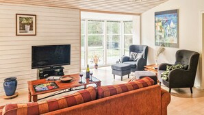 A living room with a sofa, armchairs, a TV, and a dining table with a board game. - 3 bedroom awesome home in Ebeltoft (Ebeltoft)