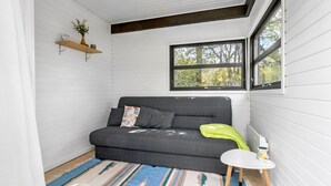A cozy room with a grey sofa, a small white table, a colorful rug, and a window with a view of trees. - 3 bedroom awesome home in Ebeltoft (Ebeltoft)