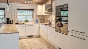 A modern kitchen with white cabinetry, a built-in oven, and a window providing natural light. - 3 bedroom awesome home in Ebeltoft (Ebeltoft)