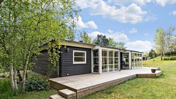 A modern house with a deck, large windows, and a grassy yard. - 3 bedroom awesome home in Ebeltoft (Ebeltoft)