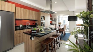 Una cocina moderna con armarios de madera, un refrigerador de acero inoxidable y una isla central con taburetes de bar.