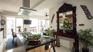 Una cocina moderna con una isla central, un espejo grande y varias plantas.
