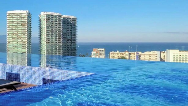 Una piscina de hotel con vistas a dos edificios altos y al océano.