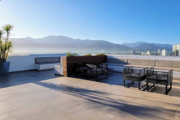 An outdoor seating area with a view of mountains and a cityscape.