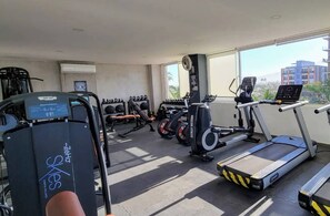 A gym with treadmills, weight machines, and dumbbells.