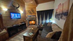 A cozy living room with a fireplace, a television mounted on the wall, and a dog resting on a couch.