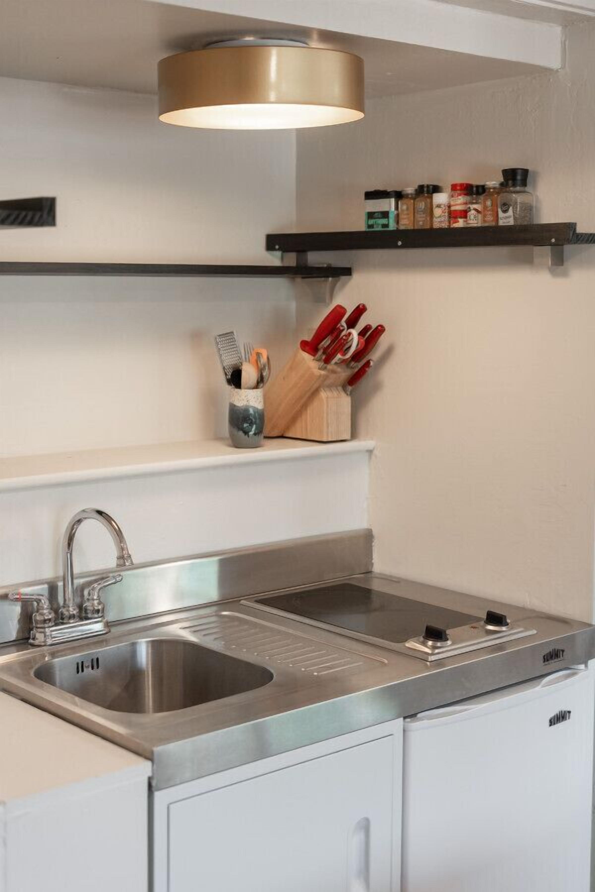 Een moderne keuken met een roestvrijstalen spoelbak, een inbouwoven en een hanglamp.