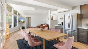 Una cocina moderna con un refrigerador de acero inoxidable grande, una mesa de comedor de madera y sillas rosadas.