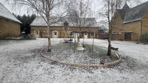 A courtyard with snow-covered ground, a gazebo, and a statue.