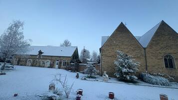 A snow-covered courtyard with a stone building and a brick building.